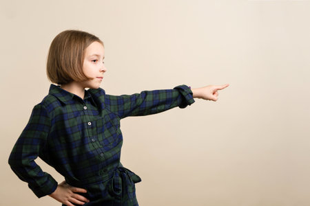 Silent introverted Kid Little Girl 9s Wearing Plaid Shirt Dress Indicates Direction. Smart Child Have Excellent Idea. Announcement Concept. Copy Space for Ad.の写真素材
