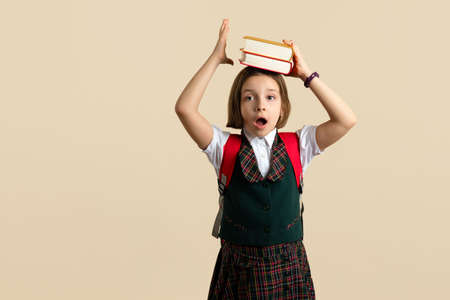 Excited Nerd Little Girl 9s wearing school uniform with two textbooks. Child have excellent idea....