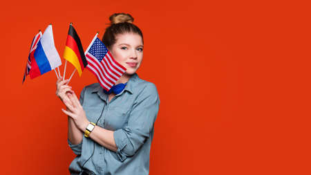 Caucasian student girl holds set small flags. Study abroad concept. International student exchange...