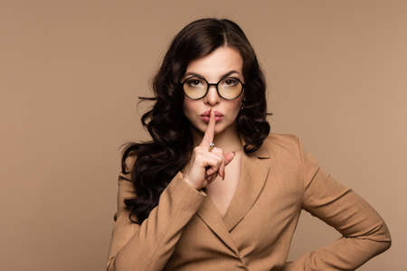 Close up portrait Young brunette woman in elegant beige dress and stylish round glasses put index...