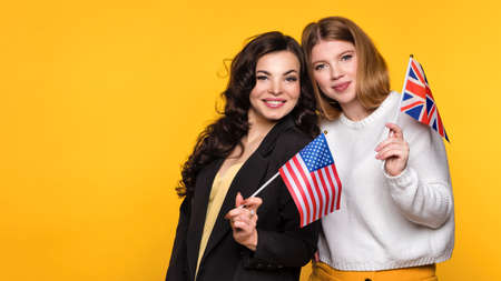 Two Girlfriends holding flags UK and USA. Study Abroad Concept. International Student Exchange...