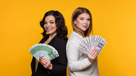 Two Delighted Girls Rejoicing Win While Holding Fans of Cash Money Dollars and Euro. Young Women...