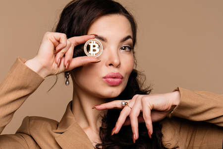 Cryptocurrency and blockchain. Girl shows btc coin holding in front of eye. Woman holding golden...