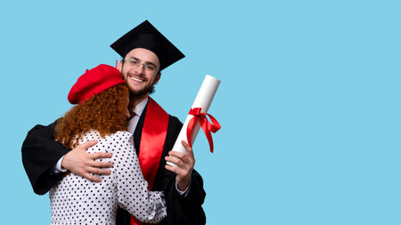 Woman in Red Beret and White Polka-dot Dress Congratulates her Boyfriend Master Degree Graduation on Blue Background. Handsome Graduate Student Male Celebrating Graduation and Getting Diplomaの写真素材
