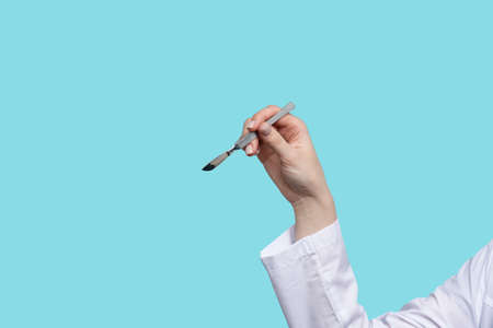 Close up Unrecognizable female surgeon holds needle holder in her hand. Doctor shows how to hold instrument correctly.の写真素材