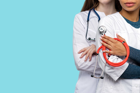 Team of unrecognizable female doctors close up with medical stethoscope on blue background in studio.の写真素材
