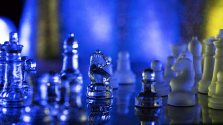 Chess game with glass transparent chess on translucent chessboard. Debut. Contrasting backlit. Knight move. Tactics and Strategy. background advertisement. Reflection pieces pawns on checkerboardの写真素材