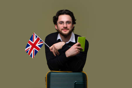 Young Male Traveler in Glasses chatting on Phone while holds Passport and Airline Boarding Pass...