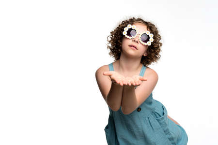 Pleasant curly short-haired female child girl 10-12 years old wears red basic t-shirt. Kind-hearted preteen schoolgirl made heart shape from two palms against chest on white background studio.の写真素材