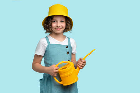 Pleasant curly short-haired female child girl 10-12 years old wears red basic t-shirt. Kind-hearted preteen schoolgirl made heart shape from two palms against chest on white background studio.の写真素材