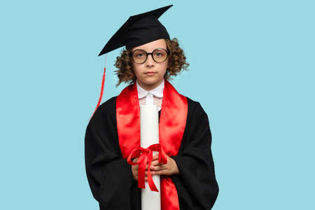 Side view curly short-haired girl 10-12s wears purple basic t-shirt and pink wireless headphones. Female child listening to music, podcast, audiobook on lilac studio background. banner advertisingの写真素材