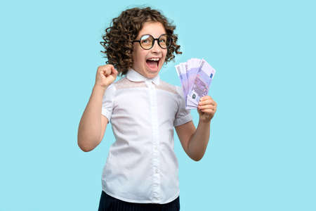 Side view curly short-haired girl 10-12s wears purple basic t-shirt and pink wireless headphones. Female child listening to music, podcast, audiobook on lilac studio background. banner advertisingの写真素材