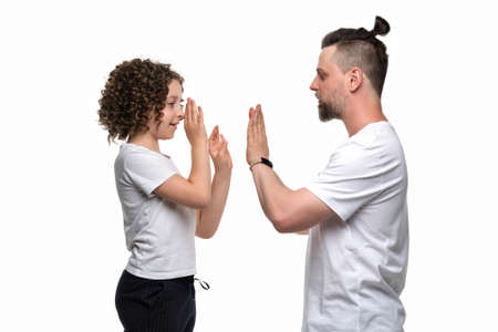Cute curly short-haired girl 10-12s lovingly hugs handsome bearded dad. Single father with adorable daughter on white studio background. Family in basic orange T-shirts. enjoy spending time togetherの写真素材