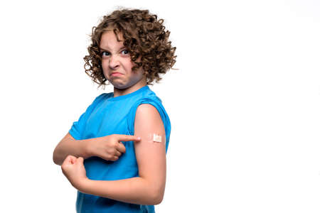 Portrait girl 12-12s in white t-shirt showing arm after Coronavirus Vaccination on light blue studio wall. Female child Got Covid-19 Vaccine Injection. Preventive Children Immunization. Revaccinationの写真素材