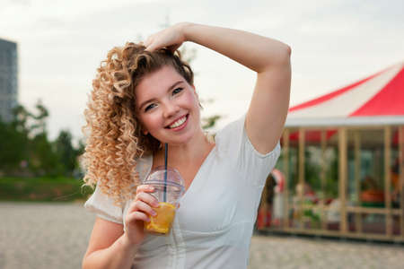 Attractive curly blonde girl talking on cell phone. Young caucasian woman at sunset summertime and sea outdoor background. Lifestyle leisure. city life conceptの写真素材