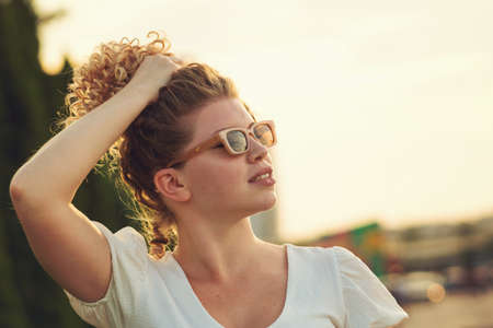 Attractive blonde curly girl in sunglasses and summer outfit enjoying lemonade, non-alcoholic...