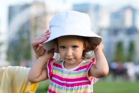 Toddler baby child girl barefoot learns to take first steps along paved footpath in summer park. Active lifestyle outdoor. Happy motherhood, childhood. back viewの写真素材