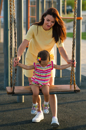 Toddler baby child girl barefoot learns to take first steps along paved footpath in summer park. Active lifestyle outdoor. Happy motherhood, childhood. back viewの写真素材