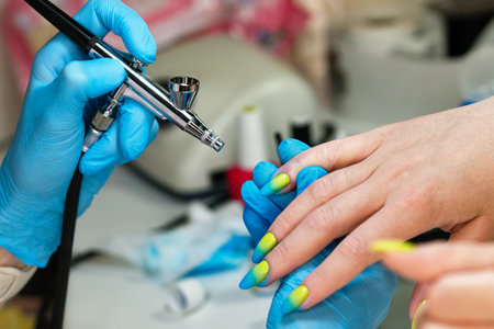 Process hardware manicure. Master manicurist in blue gloves works with milling cutter smoothes, polishes gel nail polish coating woman client nails. Electric manicure tool. healthcare fingernailsの写真素材