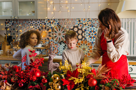 Family celebrate Christmas. Mom and children spend time in kitchen decorated for New Year holiday. Christmas Eve. Mother, son and daughter at cozy homeの写真素材