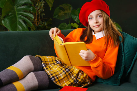 Portrait Schoolgirl reads book. Girl dressed in bright French-style outfit and red beret. retro vibe. Bookworm, book lovers and international children's book dayの写真素材