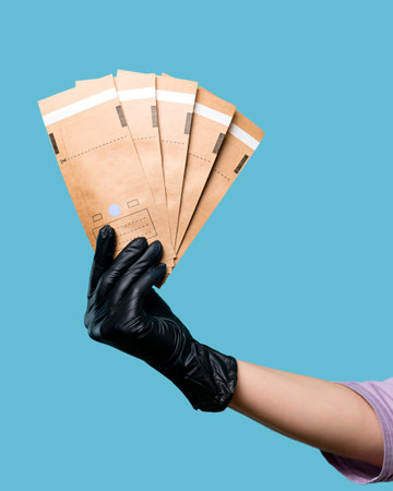 Hand of Beautician holds kraft aseptic paper bags flat self-sealing. empty space. Cosmetologist in...