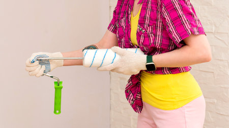 Unrecognizable woman professional house painter paint walls. Female worker refurbishes and assembles paint roller before work. Accessories for renovation apartment room. repair home conceptの写真素材