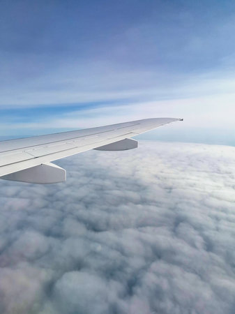 Plane is landing. Airplane wing over clouds. Aerial view through window of flying plane. Scenic view...
