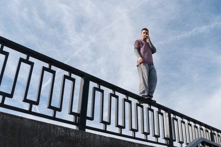 Man in sportswear smokes while standing on railing against cloudy sky. bottom view. Concept depression, sadness, loneliness and hopelessnessの写真素材