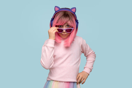 Zoomer girl with pink hair wig, 10-12 yo, wears pastel-colored clothes. Teenager on earphones looks...