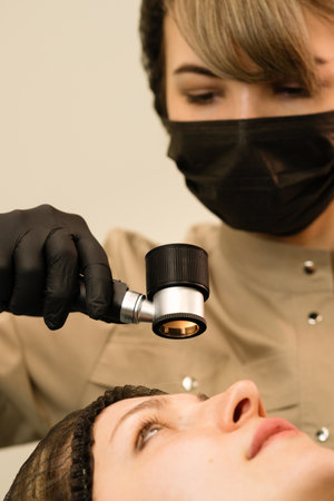 Dermatologist doctor examines moles and birthmarks of female patient in clinic. Doctor using...