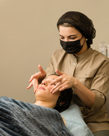 Doctor cosmetologist doing facial massage for teen girl in spa salon. Skincare by cosmetician.の写真素材