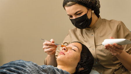 Dermatologist applying cosmetic acne preparation on face teen girl in spa salon. Cleaning face...