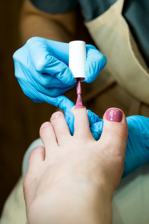 Pedicure. Chiropody. Coating with colored base applying gel polishの写真素材