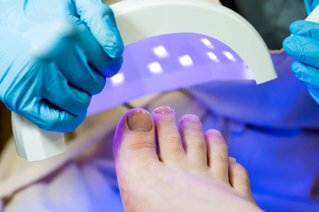 Procedure Pedicure. Stage of applying gel polish. Drying the base layer under a UV lamp. Customer's point of viewの写真素材