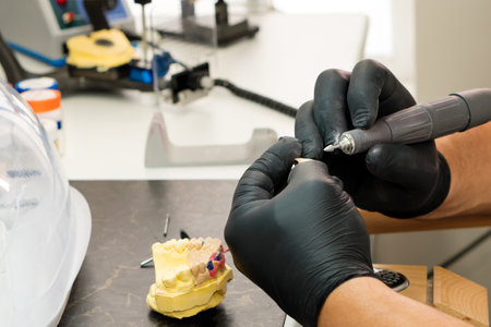 Manufacturing of dentures close up. Dental technician worker working on the denture, false teeth....