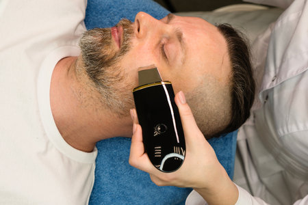 Man during ultrasonic face peeling procedure in beauty clinic