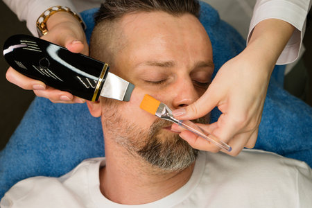 Man during ultrasonic face peeling procedure in beauty clinicの写真素材