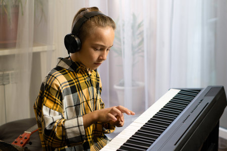 A young musician with headphones intently playing an electric pianoの写真素材