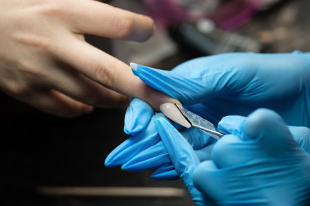 Manicurist skillfully shapes an edge nail with a metal tool.の写真素材