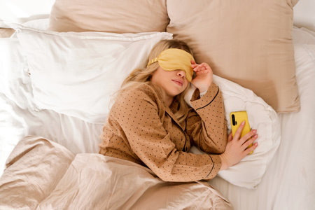Sleeping with smartphone after waking up. Healthy sleep for a young, attractive woman
