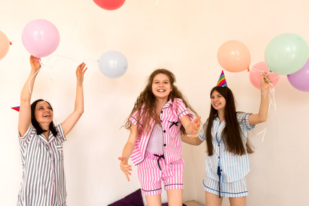 Joyful family in party hats playing with balloons indoors. Bedroom Balloon Pajama Partyの写真素材