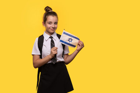 A schoolgirl proudly holds an Israeli flag while smiling.の写真素材