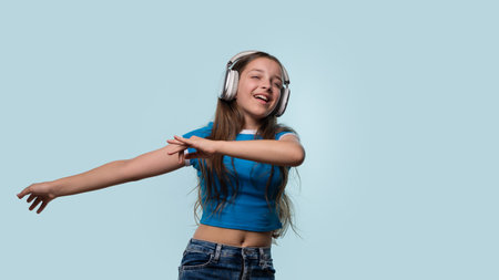 Girl in blue shirt wearing white headphones while dancing.の写真素材