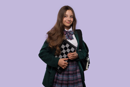 A smiling schoolgirl holds a chessboard while posing confidently.の写真素材