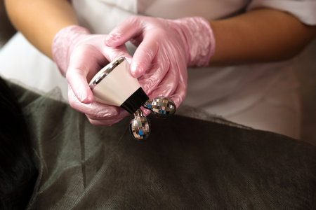 Close-up of a beautician holding a microcurrent massager during a facial session.の写真素材