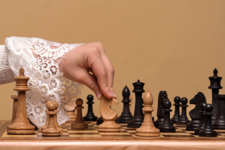 Close-up of hand in lace blouse moving a chess piece on board.の写真素材