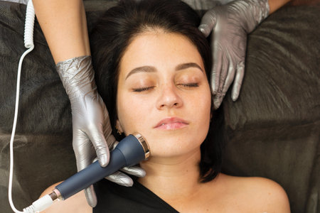 Close-up of a woman receiving phonophoresis ultrasound facial treatment during a skincare session. Hardware anti-aging cosmetic procedureの写真素材