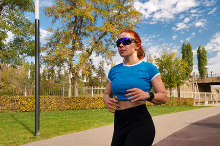 Young woman jogging in a park, focused on her fitness routine.