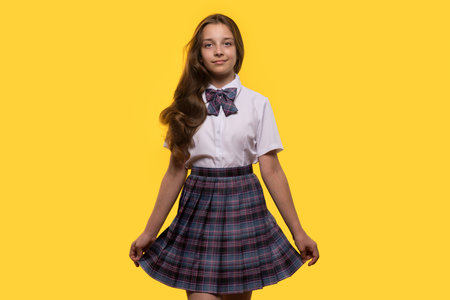 A schoolgirl poses gracefully in a plaid skirt, smiling confidently.の写真素材